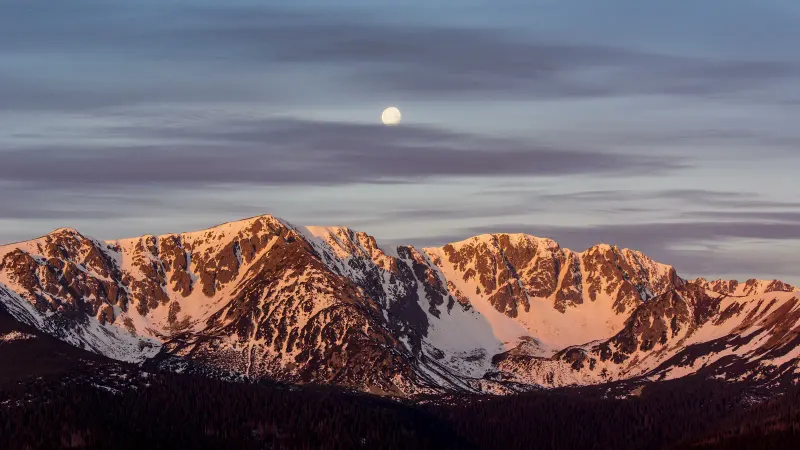 A snow ridge in the first red light of sunrise, the moon above it — a frame of my timelapse.